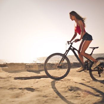 Vrouw op fiets op het strand